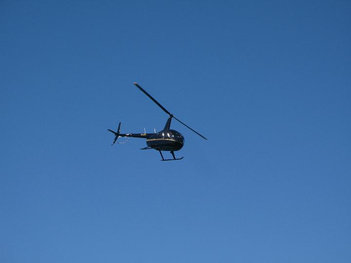 Black Helicopter Flying up in the Blue Gray Sky, Emphasizing Copy Space.