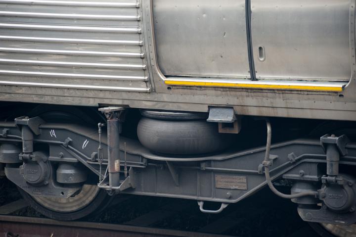 Detail of Silver Colored Train Car Wheels and Braking Mechanism Below Passenger Doors