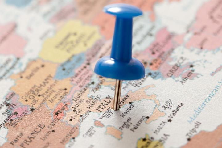 Close Up of Blue Pin Tacked into Map Locating City of Rome, Italy in Trip Planning Concept Image