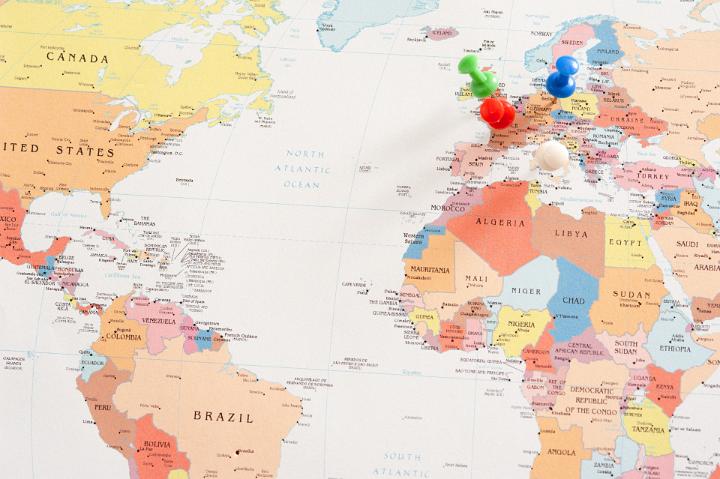 Map of the World with Different Colored Pins Inserted in Various Locations Throughout Europe in International Travel or Business Concept Image