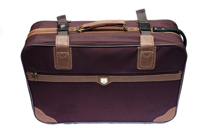 Isolated retro brown suitcase with leather straps and corner protectors viewed high angle on white conceptual of travel and vacations